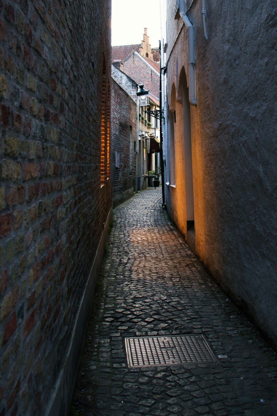 Narrow cobblestone alley at dusk with warm window lights